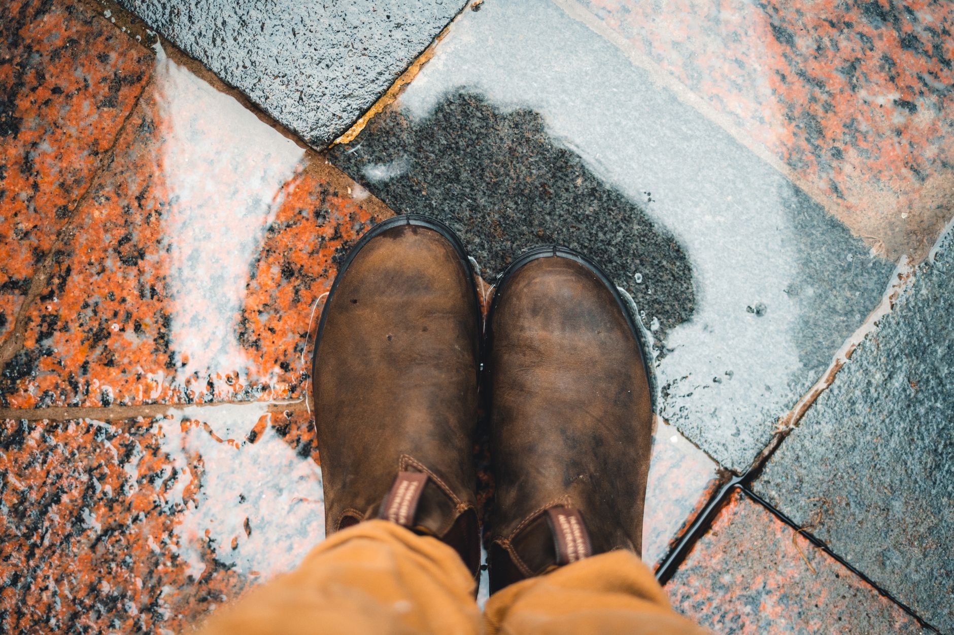 Des chaussures de marche posées sur un trottoir mouillé par la pluie